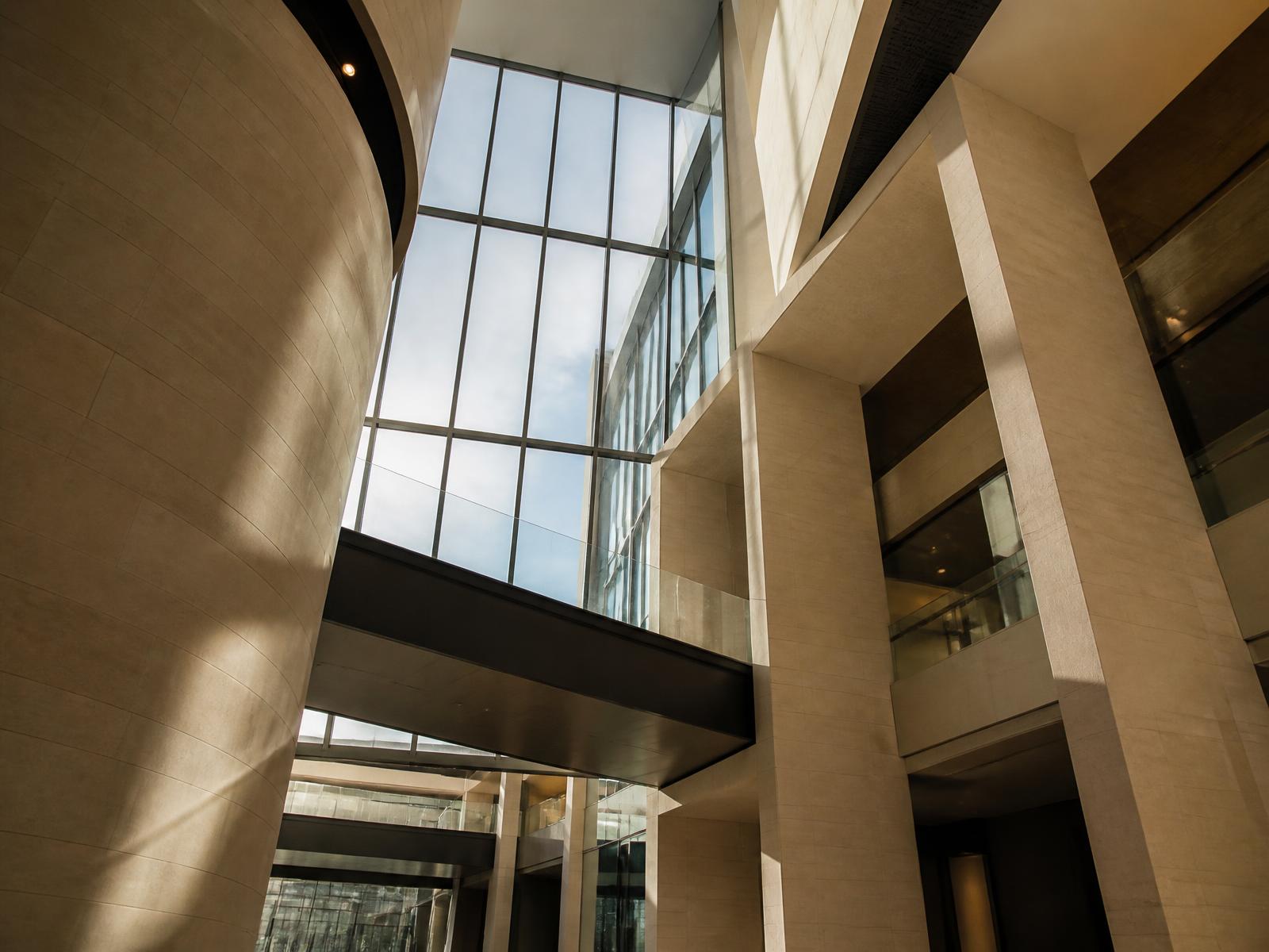 Modern corporate atrium in warm stone and glass